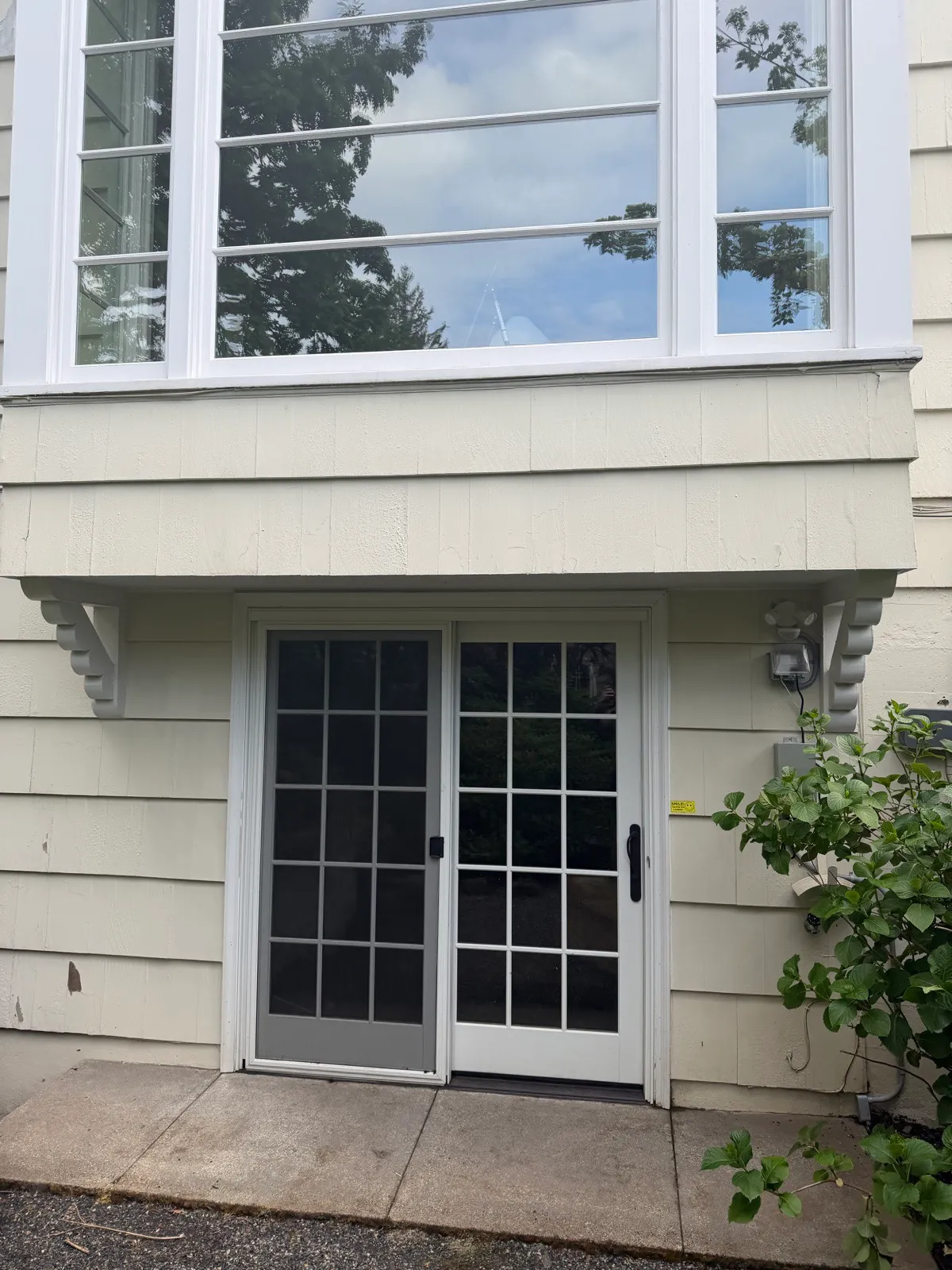 Cream lap siding below a bay window, bright and streak-free after a soft wash