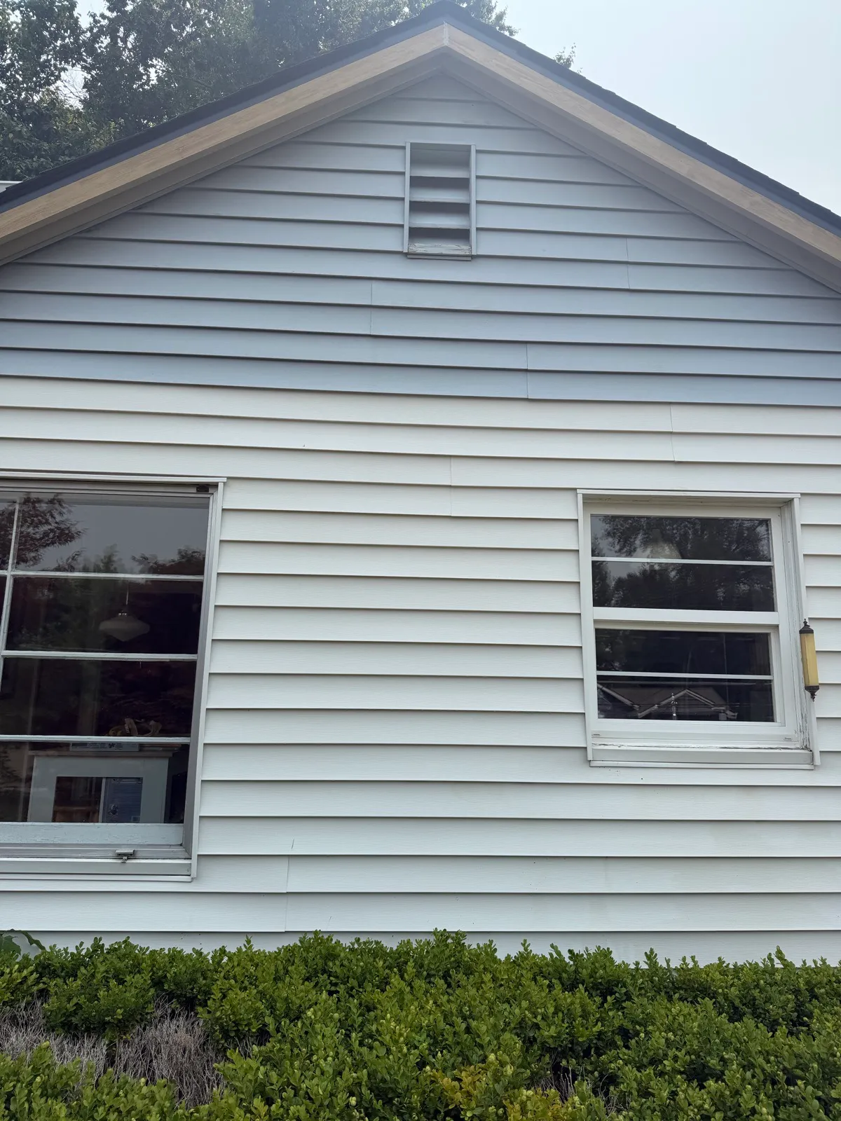 White lap siding on a gable end, clean and bright after a low-pressure soft wash