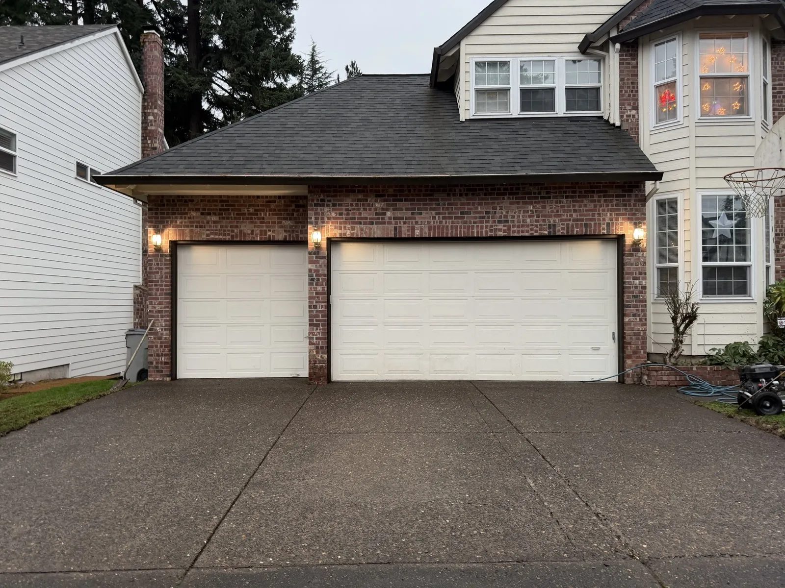 After: the same driveway fully clean at dusk with the garage lights on